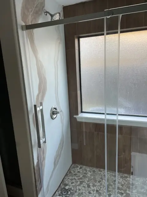 Shower with marble pattern walls and pebble floor